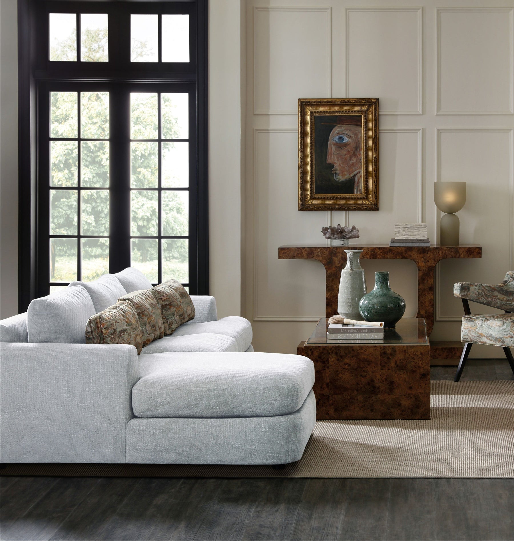 An artfully layered living room with a pale sectional, sculptural burl wood tables, and collected objects